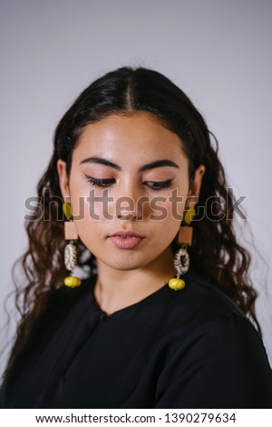 Studio portrait of a beautiful, young and attractive Malay Asian woman in a traditional black dress (Baju Kurung) for Raya (Eid) against a white background. She is youthful and radiant. 