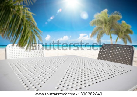 Table background of free space for your decoration. Blurred background of beach with green coco palms. Sunny day with blue sky and sun light. Summer time 