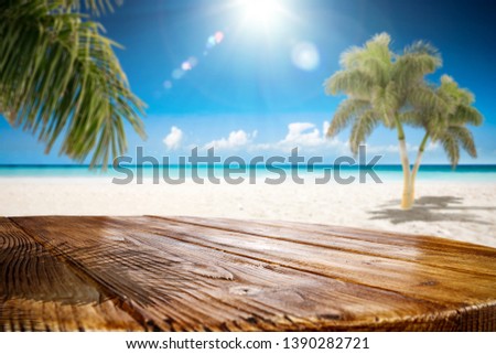 Table background of free space for your decoration. Blurred background of beach with green coco palms. Sunny day with blue sky and sun light. Summer time 