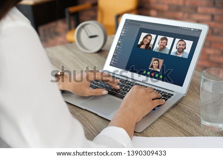 Woman having video chat with colleagues at table in office, closeup Royalty-Free Stock Photo #1390309433