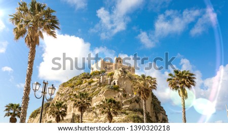 Tropea city in Calabria, Italy. View of the ancient castle on the cliff, the rocks, the sea, and the beach. Summer Tourist destination. Lens flare in post production.