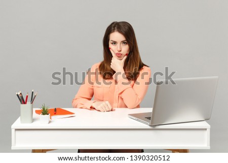 Young attractive woman in pastel casual clothes put hand prop up on chin sit work at desk with pc laptop isolated on gray background. Achievement business career lifestyle concept. Mock up copy space