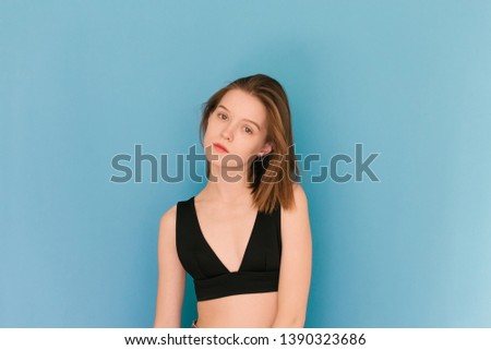 Girl of model appearance on a blue background in a bra, looks into the camera and poses on the camera. Model tests for the agency. Model's snapshots. Snaps for agency.