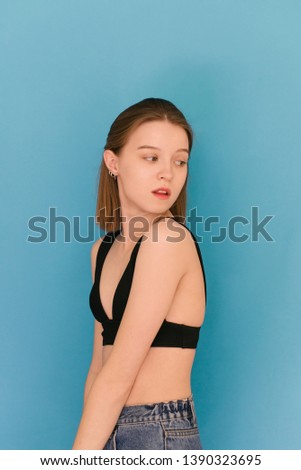 Portrait of an attractive model poses on a blue background for a model agency. Beautiful girl model looks on a blue background. Model tests. Vertical photo