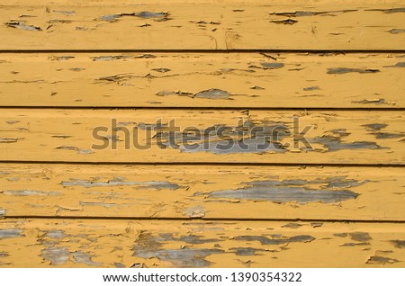 Yellow wooden background with peeled pieces of old paint.