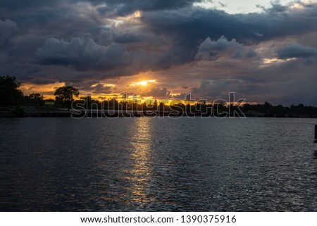 colorful sunset over the sea lake with dark red clouds in summer