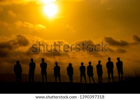 The silhouette of a group of people is celebrating success on the hilltop.
