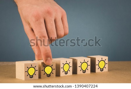 the hand makes a choice and chooses a burning light bulb, a symbol of a fresh idea.