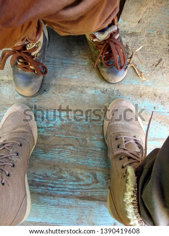 Big and small legs in shoes on wooden floor. Top down view adult and child feet