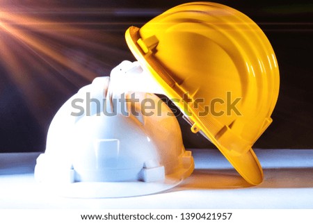 Protective helmet for the head of yellow and white plastic resting on a white surface with a black background. Flare in post production.
