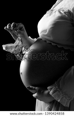 close-up of woman pregnant belly with a toy pram. Girl tenderly holding her tummy with child. Concept of pregnancy, mother's love and happy motherhood