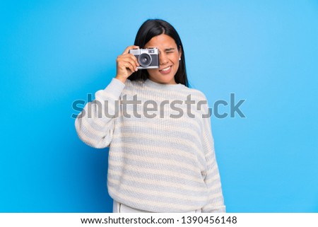 Young Colombian girl with sweater holding a camera