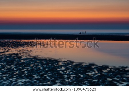 Silhouettes of fishermen during dramatic sunset on a sandbank