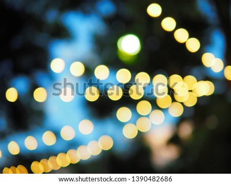 Yellow bokeh defocused lights with blurred background of silhouette big trees and twilight sky. Space for text, article layout, abstract background for design.