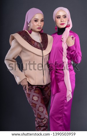 Beautiful female models wearing designer dress for Muslim woman isolated over grey background. Eidul fitri fashion and beauty concept.