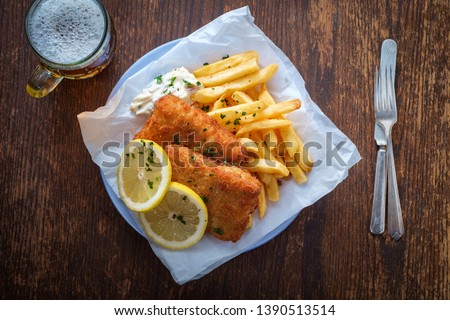 Authentic traditional British cuisine fish and chips served with an ice cold beer Royalty-Free Stock Photo #1390513514
