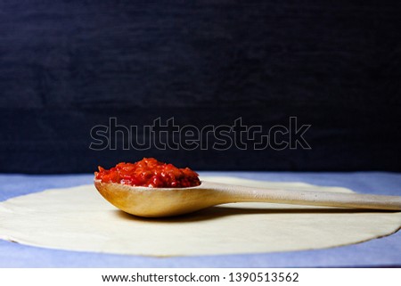 WOODEN SPOON WITH FILLED PEPPERS,ONION AND TOMATO OVER FLOUR MASS