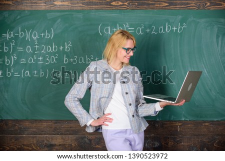 Basic school education. Teacher elegant lady with modern laptop surfing internet chalkboard background. Distance education concept. Woman teacher wear eyeglasses holds laptop surfing internet.