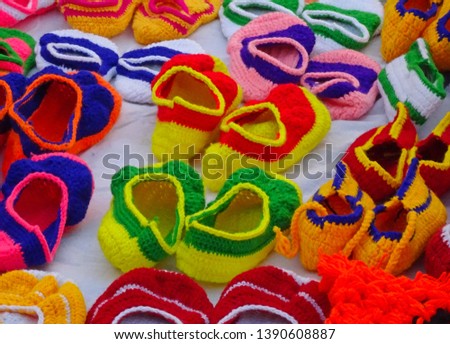 Beautiful and colorful handmade hand crafted woolen infant newborn baby footwear boots for show and sale at a stall in India. Intentionally blurred.