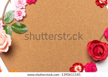 Frame made of rose flowers on cork board  background. Top view with copy space. Flat lay design concept.
