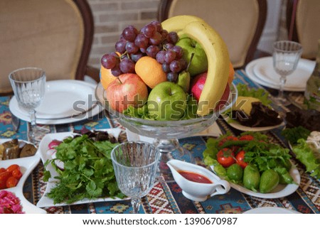Red and blue apple, orange, red banana banana. Cucumber, tomato, greens, radish. Fruit in a bowl .