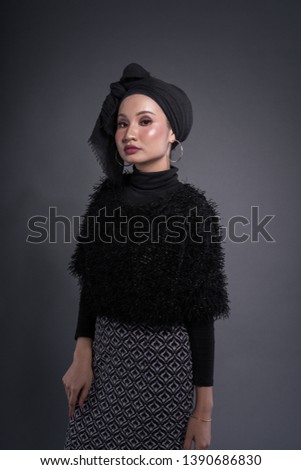 Beautiful Muslim female model wearing floral skirt, black shirt with hijab, isolated over grey background. Studio fashion and beauty concept