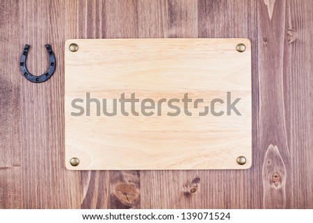 Wooden sign board with horseshoe on wood wall background