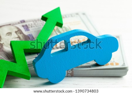 Green arrow graphic up on the background of the car and a stack of money cash dollars. The concept of the growth of the car market, insurance, price growth, repair costs