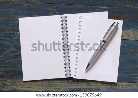 spiral notebook with pen on wooden background
