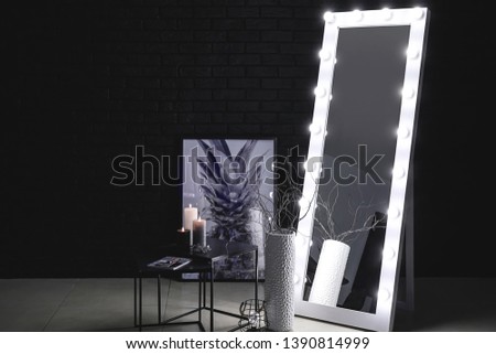 Big mirror with table near dark wall in room