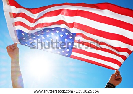 Close up shot of man hands holding United State of America flag waving on the wind, clear blue sky. Patriotic background for 4th of july USA Independence day with copy space for text.