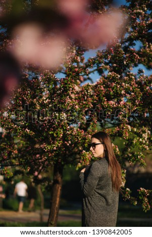 Attractive girl stand in front of beautiful blooming tree