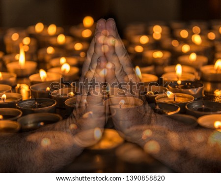 Praying hands over burning candles