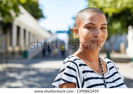 Portrait of young happy bald woman on city street looking at camera. Confident stylish girl outdoor with copy space. Proud and satisfied black curvy woman standing on street. Royalty-Free Stock Photo #1390862459
