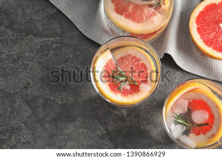 Glasses of infused water with grapefruit slices on grey table, flat lay. Space for text