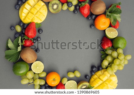 Creative layout made of summer fruits, frame. Tropical flat lay. Grapes, mango, strawberry, blueberry, mint, lime, citrus fruits on blue background. Copy space
