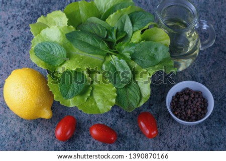 Ingredients for making salad - different fresh leaves, tomatoes and spices on a wooden table