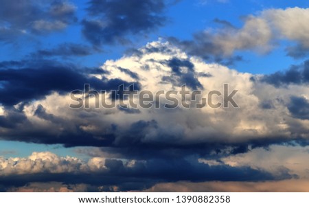Interesting white and dark mixed cloud formations on a blue sky in spring