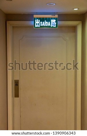 A hotel in Macau leads to a safe passage door. The safety exit sign uses Chinese and Portuguese.
