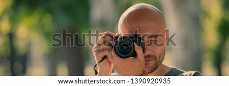 photographer with a camera on the background of the park. Web banner for your design.