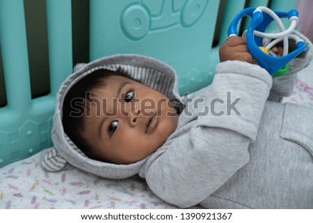 cute little asin baby boy lying on soft blanket and play toy