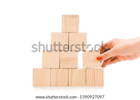 cropped view of woman picking up one wooden block with copy space from pyramid isolated on white