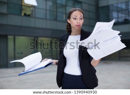 Serious female employee is dissatisfied of the results of the financial report outdoors.