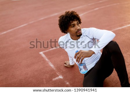 Close up of attractive black man with curly hair sitting on the basketball court