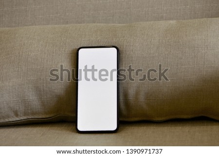 Edge to edge full screen smartphone with copy space on sofa, cozy feeling.