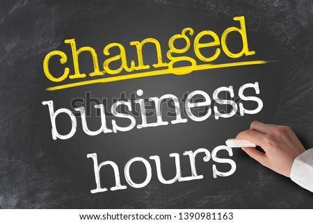 text CHANGED BUSINESS HOURS written on blackboard with hand holding piece of chalk Royalty-Free Stock Photo #1390981163