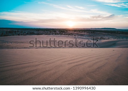 Landscape of sun over skyline in desert at White Sand Dunes Mui Ne, Vietnam. Countryside panorama under scenic colorful sky at sunset dawn sunrise. Beautiful view of bright dramatic sky dark ground