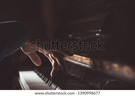 one male hand on the piano. The palm lies on the keys and plays the keyboard instrument in the music school. student learns to play. hands pianist. black dark background.