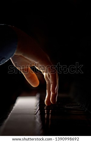 one male hand on the piano. The palm lies on the keys and plays the keyboard instrument in the music school. student learns to play. hands pianist. black dark background. vertical.