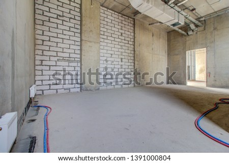 Layout of building materials bricks. unfinished, incomplete, pending. Monolithic brick basement wall. heating pipes lie on floor. New empty room. Сonstruction stage of residential monolithic house.
